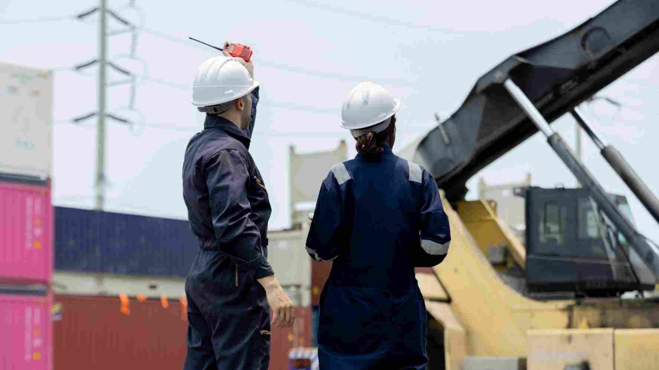 Two,Engineers,Industrial,Workers,In,Safety,Helmets,And,Coveralls,Stand