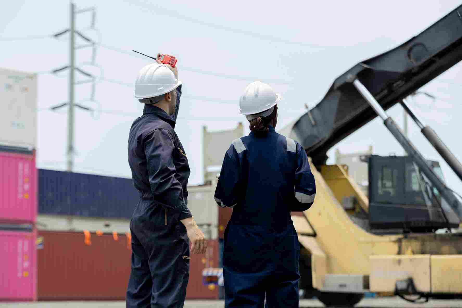 Two,Engineers,Industrial,Workers,In,Safety,Helmets,And,Coveralls,Stand